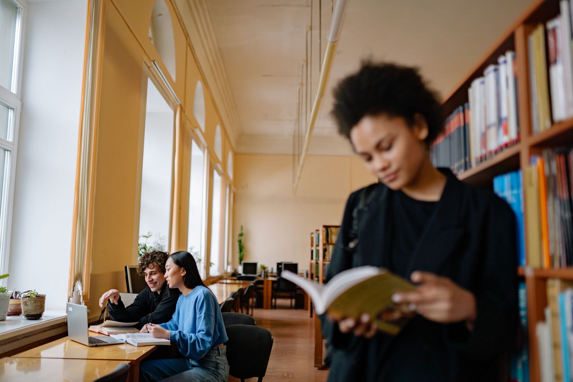 Students studying with books and laptops in a university library