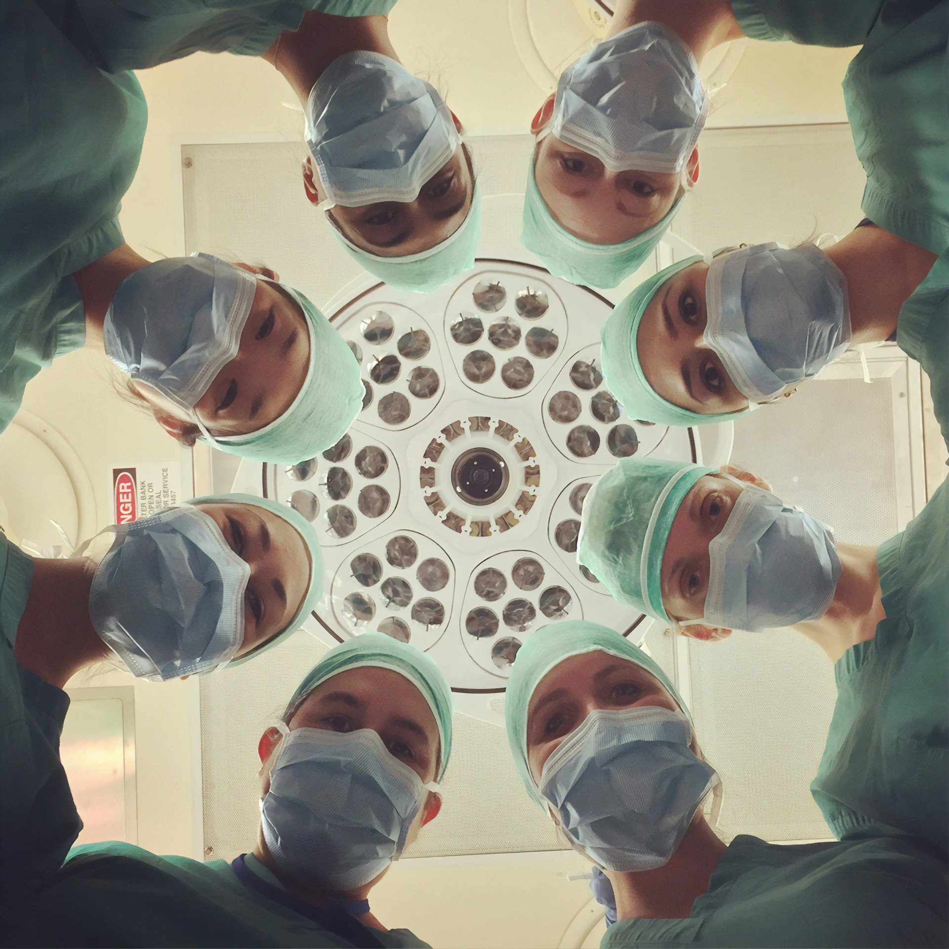 A surgical team in caps and masks looking down toward the camera