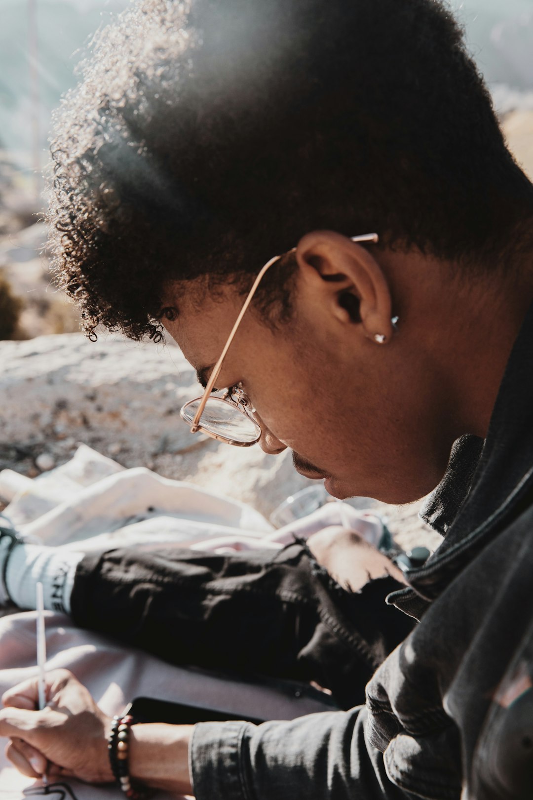A student in a hooded sweatshirt reading a book