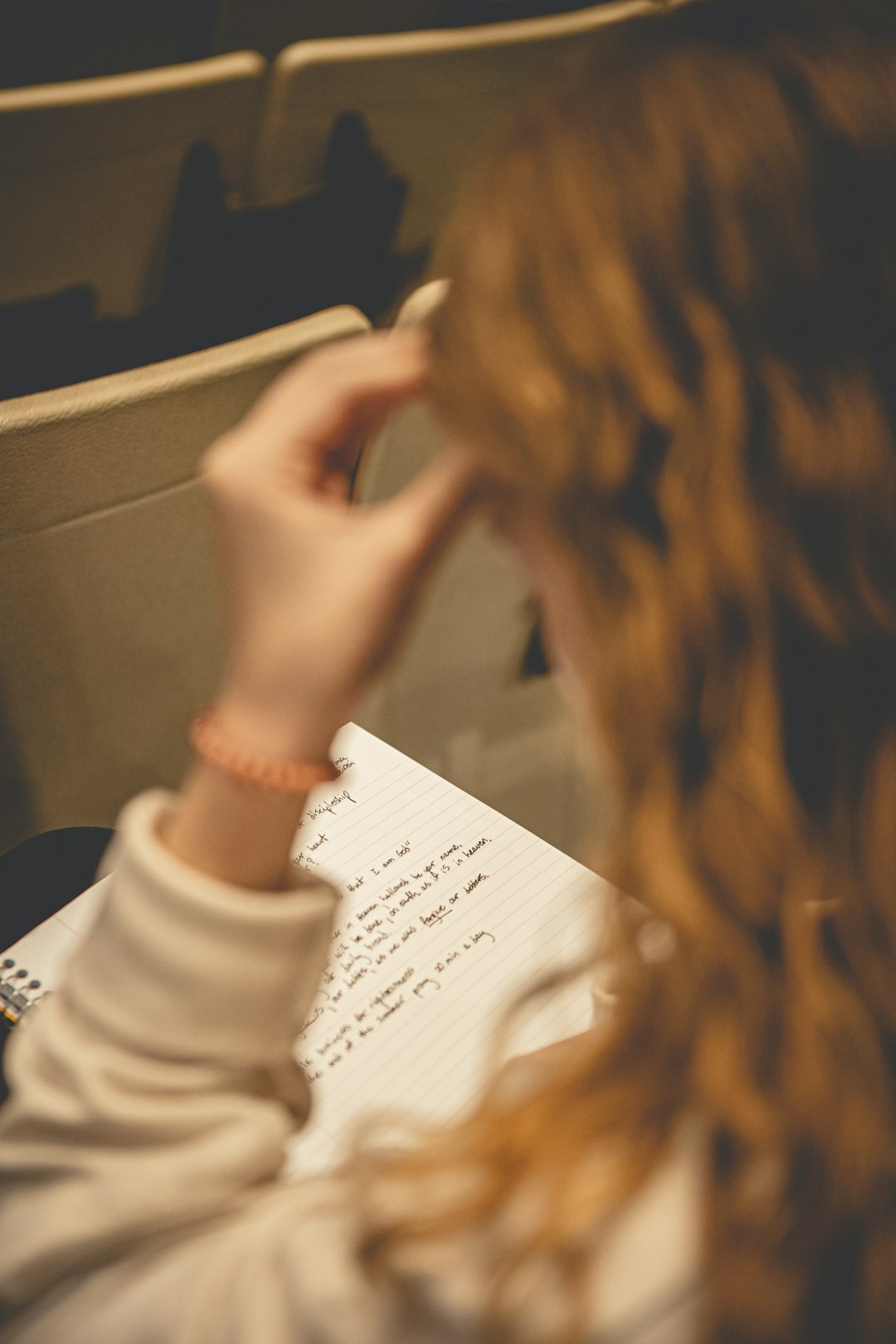 A student sitting at a table writing notes on paper