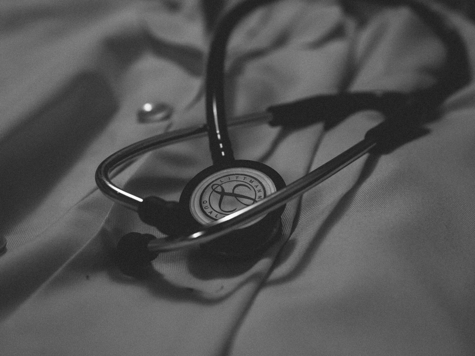 A stethoscope resting on a folded medical coat, black and white